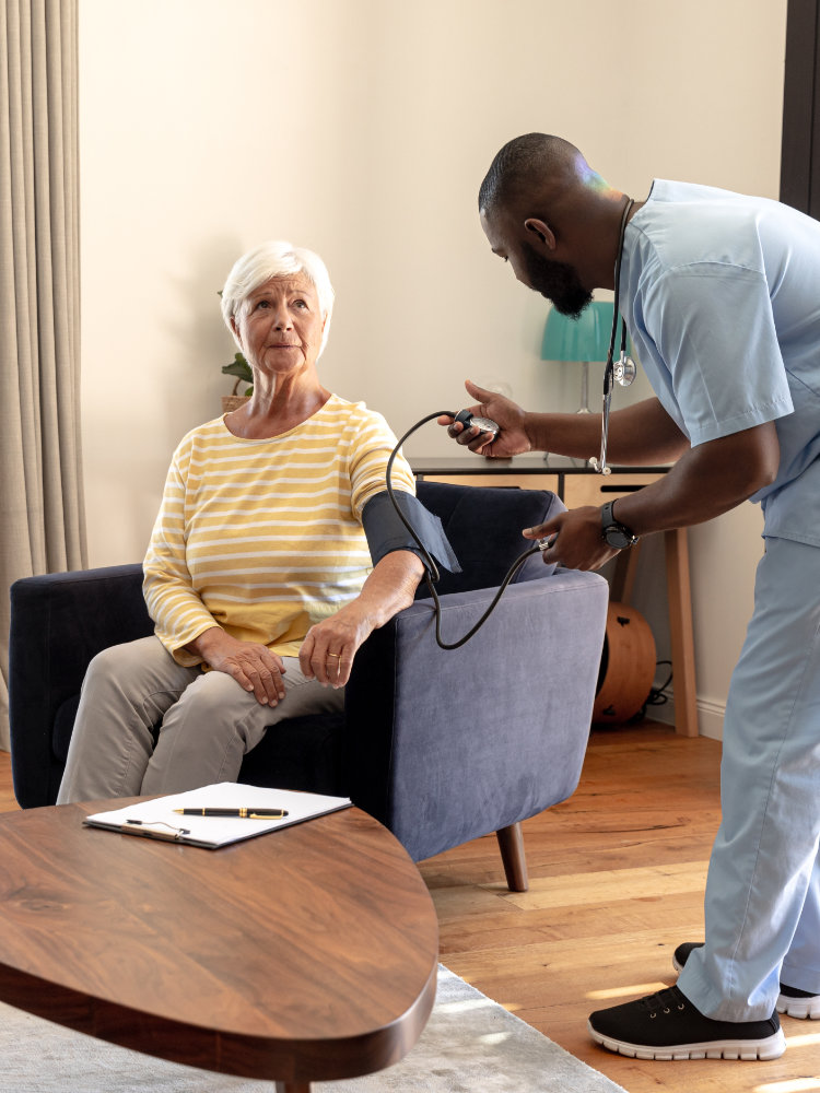 African American male nurse checking woman's blood pressure in her home.