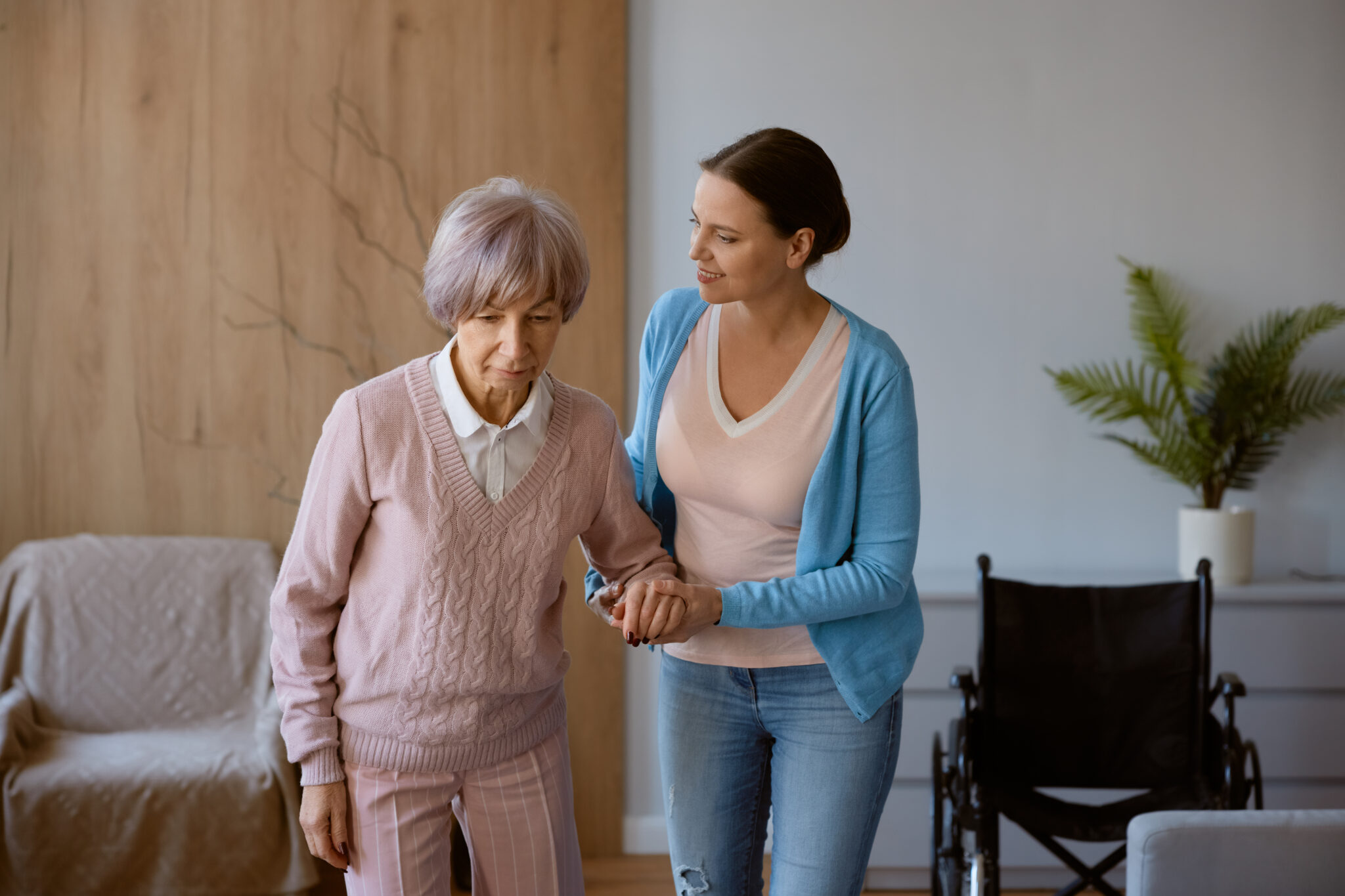Young female caregiver helping Asia elderly women from her wheelchair.