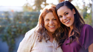 Senior Hispanic mother with adult daughter helping her at home.