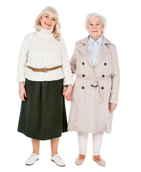 cheerful retired women holding hands isolated on white