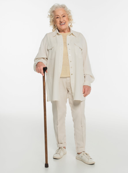 smiling elderly woman in casual clothes standing with walking stick